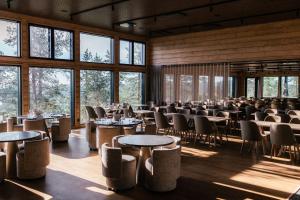 a dining room with tables and chairs and windows at Kaamos Lodge in Aavasaksa