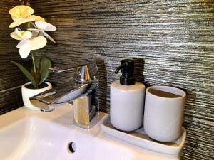 a bathroom sink with two cups and a faucet at Elite Residence - Modern 2BR - Sleeps 6 - FREE Parking in Timişoara +16 photos