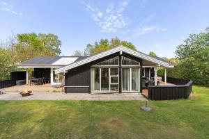 a black house with a patio and grass at 8522-Grenaa-Nobilisvej-15 in Grenå