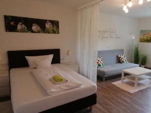 a bedroom with a white bed and a couch at HOTEL SPATZENNEST Vogelsberg in Herbstein