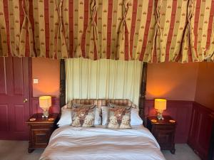 a bedroom with a bed with two lamps on tables at The Hunters Rest Inn in Clutton