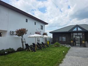 a yard with chairs and umbrellas in front of a house at BLACK SEA HOUSE in Vama Veche