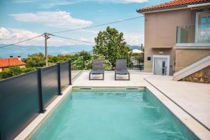 a swimming pool on a balcony with two chairs at Apartments Petra in Risika