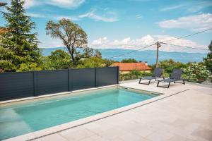 a swimming pool with two chairs and a fence at Apartments Petra in Risika