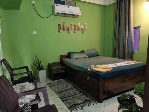 a green room with a bed and a chair at SH Homestay in Tezpur