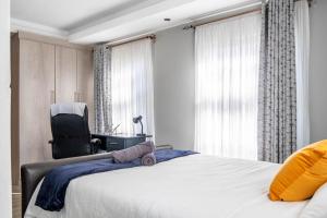 a bedroom with a bed and a chair next to a window at Red Pillar in Maseru