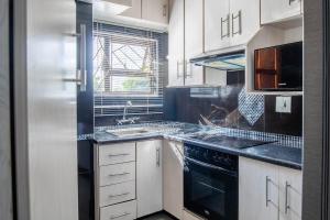 a kitchen with white cabinets and a black stove top oven at Red Pillar in Maseru