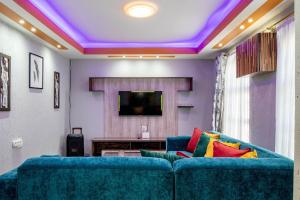 a living room with a blue couch and a tv at Red Pillar in Maseru