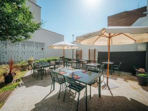 a patio with tables and chairs and umbrellas at ibis Styles Lens Centre Gare in Lens