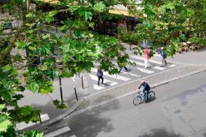 a man riding a bike on a crosswalk in a street at Hipotel Paris Gambetta République in Paris