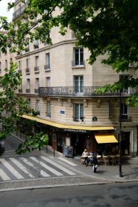 a building with tables and chairs in front of it at Hipotel Paris Gambetta République in Paris