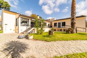 an exterior view of a house with a palm tree at Villa Praia e Floresta in Aroeira