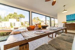 a dining room with a wooden table and large windows at Villa Praia e Floresta in Aroeira