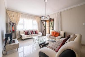 a living room with two couches and a tv at Siyajabula Guesthouse in Howick