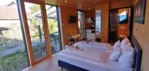 a bedroom with a large white bed and large windows at HOTEL SPATZENNEST Vogelsberg in Herbstein