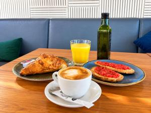 a table with a cup of coffee and a plate of food at Malvarrosa Beach Rooms in Valencia +27 photos