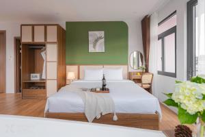 a bedroom with a large bed and a green wall at Nature Hotel - Le Hong Phong in Da Lat