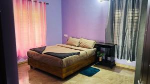 a bedroom with purple walls and a bed with a table at Moonlight mist wayanad in Vaduvanchal