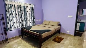 a small bed in a room with purple walls at Moonlight mist wayanad in Vaduvanchal