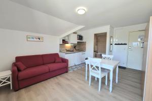 a living room with a red couch and a table at Studio 2 pers avec accès piscine et sauna in Les Déserts