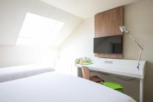 a bedroom with a bed and a desk with a tv at Campanile Evry Ouest - Corbeil Essonnes in Corbeil-Essonnes