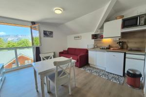 a kitchen and living room with a table and a red couch at Studio 2 pers avec accès piscine et sauna in Les Déserts