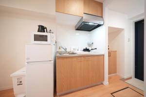 a kitchen with a white refrigerator and a microwave at Hotel Otsukahouse in Tokyo