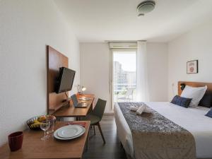 a hotel room with a bed and a desk with a computer at Séjours & Affaires Grenoble Marie Curie in Grenoble