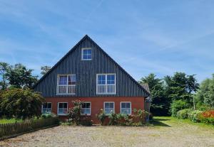 a large house with a gambrel roof at Ferienhof Peter in Vollerwiek