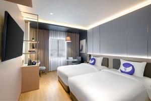 a hotel room with two beds and a television at Fox Hotel Nagoya Batam in Nagoya