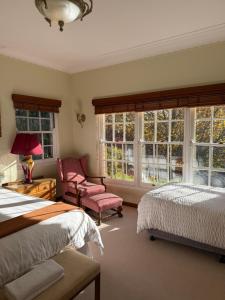 a bedroom with two beds and a chair and windows at Echo Point Cottage in Katoomba