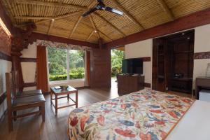 a bedroom with a bed and a table and a television at Summit Green Lake Tea Resort & Spa in Jakhalābāndha