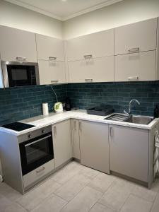 a kitchen with white cabinets and a sink at Léna's apartman in Pécs
