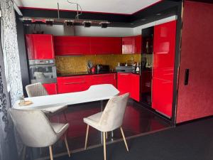 a red kitchen with red cabinets and white chairs at Aiavilja Red Pearl Apartment in Paide
