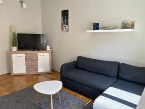 a living room with a blue couch and a tv at Léna's apartman in Pécs