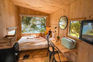 a woman sitting on a bed in a tiny house at Kampaoh Las Arenas in Pechón