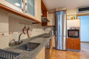 a kitchen with a sink and a stainless steel refrigerator at Apartamento familiar acogedor in Ordes