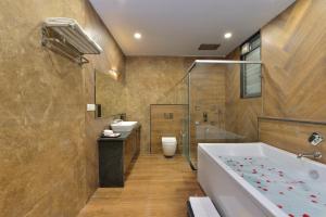 a bathroom with a tub and a toilet and a sink at Ginger Gadchiroli in Garhchiroli
