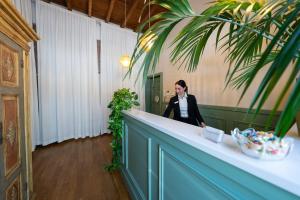 a woman standing at a counter in a room with a palm tree at La Maison del Capestrano in Milan