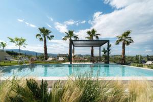 a swimming pool with palm trees and a gazebo at Ammosphere in Nea Peramos