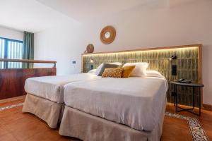 a bedroom with a large white bed with a clock on the wall at Estival Park Marena in La Pineda