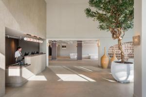 a woman sitting at a desk in a lobby with a tree at Estival Maramar in Comarruga