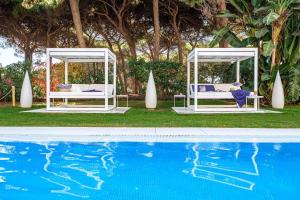 a pool with two beds next to a pool of water at Estival Isla Cristina in Isla Cristina