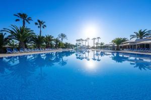a large swimming pool with palm trees and chairs at Camping Estival Vendrell Platja in Comarruga