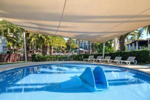 a swimming pool with a blue recliner in a resort at Estival Islantilla in Islantilla