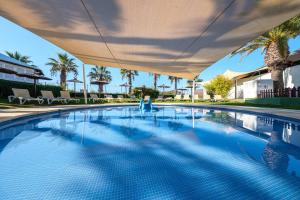 a swimming pool with an umbrella over it at Estival Islantilla in Islantilla