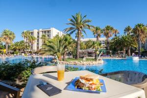a table with a sandwich and a drink next to a pool at Estival Islantilla in Islantilla