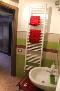 un baño con lavabo y toallas rojas en un estante. en Gombereto 10, en Bagni di Lucca