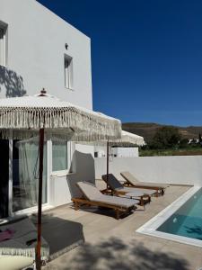 Eine Gruppe von Stühlen und Sonnenschirmen neben einem Schwimmbecken in der Unterkunft Merichas Luxurious Villa in Kythnos