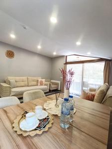 a living room with a wooden table with plates and water bottles at Han PANSİYON in Çaykara